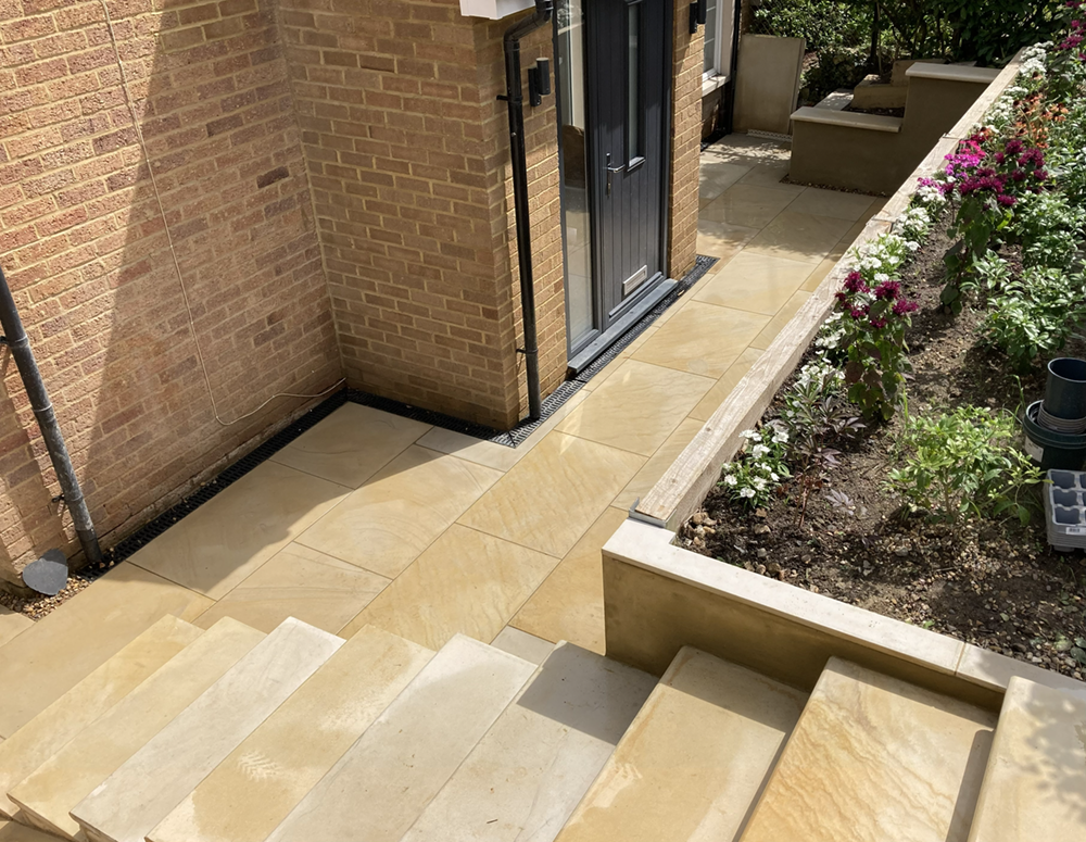 Buff sandstone split-level patio with integrated steps and rendered walls